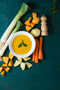 Freshly made pumpkin purée with its ingredients on a green background