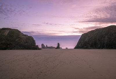 Rocks on beach against sky during sunset