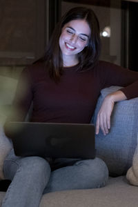 Portrait of young woman sitting on sofa at home