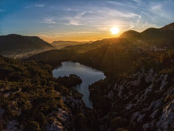 Scenic view of lake and mountains against sky during sunset