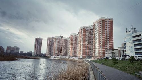 Buildings by river against sky in city