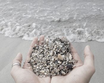 Close-up of hand holding sand at beach