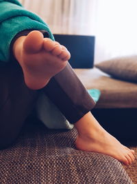 Low section of boy relaxing on bed at home