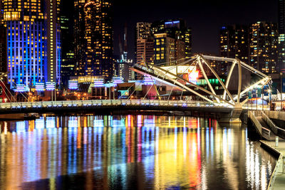 Illuminated bridge over river and buildings at night