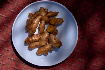High angle view of ginger in plate on red floor