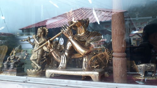 Statue against temple seen through glass window