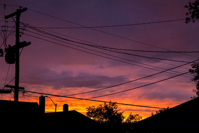 Low angle view of silhouette cables against sunset sky