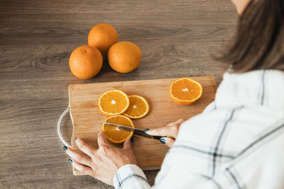 Midsection of woman holding oranges on table