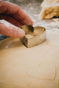 Person making heart-shaped cookies using a cookie cutter