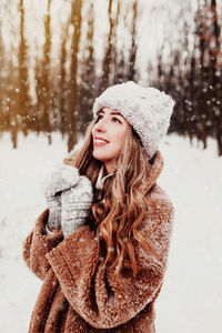 Portrait of young woman standing against trees