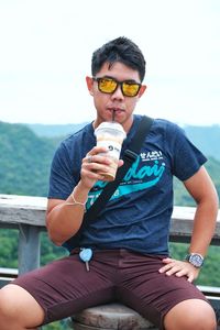 Full length of man holding food while sitting outdoors