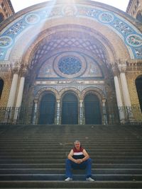 Full length of man sitting on staircase against historic building