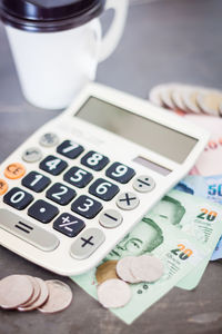 Coins with calculator and paper currencies on table