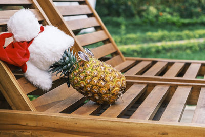 Side view of relaxing funny pineapple wearing sunglasses and santa claus hat lies on sun lounger 