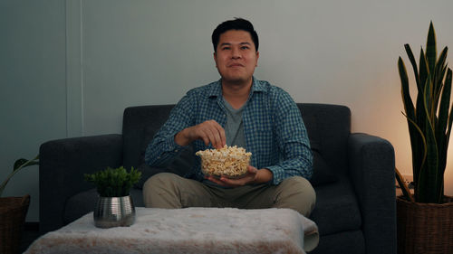 Man looking away while sitting on sofa at home