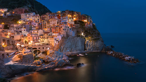 Aerial view of illuminated buildings by sea