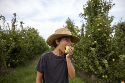 A boy biting an apple he has just picked from the tree