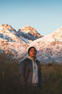 Portrait of young man standing on mountain against clear sky