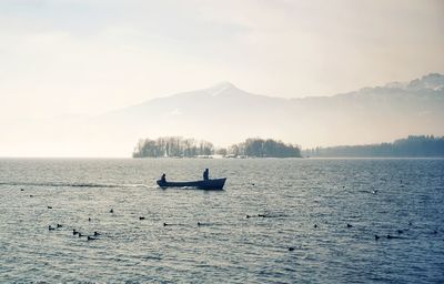 People on boat in sea against sky