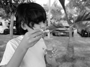 Close-up of girl blowing on bubble wand in park