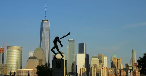 Statue in city against clear sky