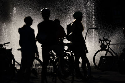 Silhouette people on bicycle at night