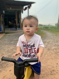 Portrait of boy holding camera while standing outdoors