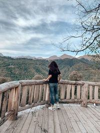 Rear view of woman standing on railing against mountain