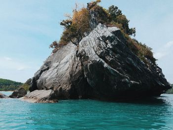 Rock formation by sea against sky