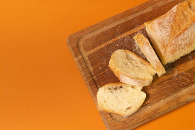 Close-up of bread on cutting board against orange background
