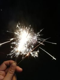 Person hand holding firework display against black background