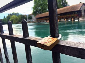 Close-up of padlock on railing against lake