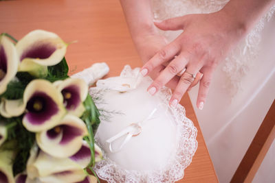 Midsection of bride removing ring on pillow