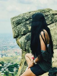 Rear view of woman looking at cityscape against sky