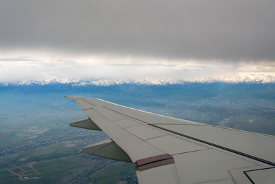 Airplane flying over mountain against sky