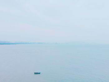 Rowboat moored in sea against sky during foggy weather