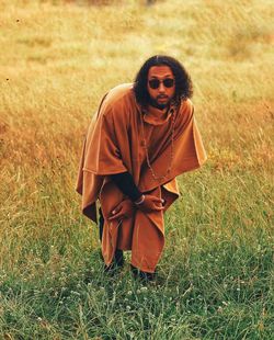 Portrait of man wearing traditional clothing and sunglasses standing on grassy field