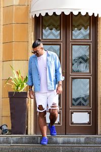 Full length of young man standing against window