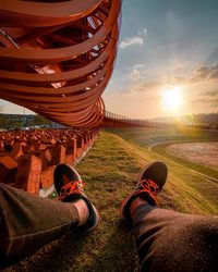 Low section of person on field against sky during sunset