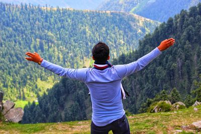 Rear view of man with arms outstretched standing on mountain