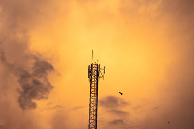 Low angle view of communications tower against sky during sunset