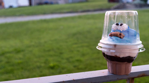 Close-up of ice cream in container on railing