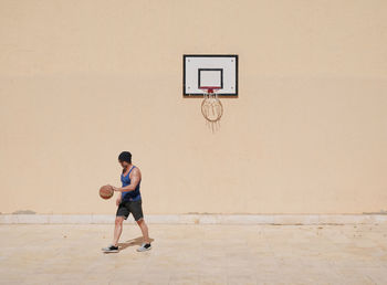 Full length of man playing with basketball