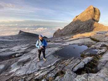 Full length of man on rock at shore against sky