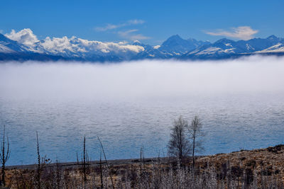 Scenic view of lake by snowcapped mountains against sky