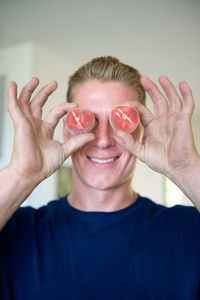 Portrait of man holding peaches over eyes