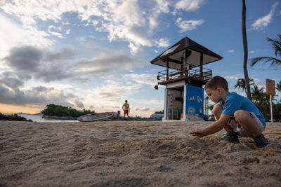 Boy playing on beach against sky