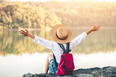 Rear view of woman with hat sitting in lake
