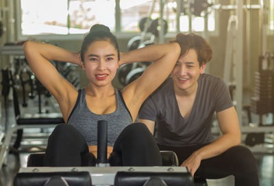 Instructor assisting woman exercising in gym