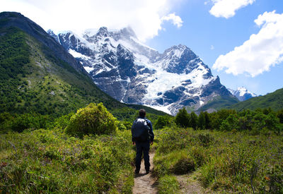 Rear view of man standing on mountain against sky